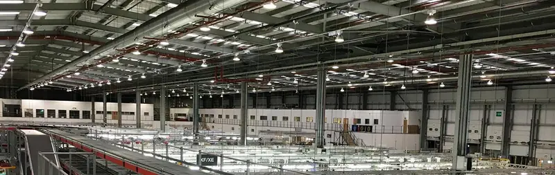 Interior of a large commercial warehouse with rows of high bay and linear LED lighting
